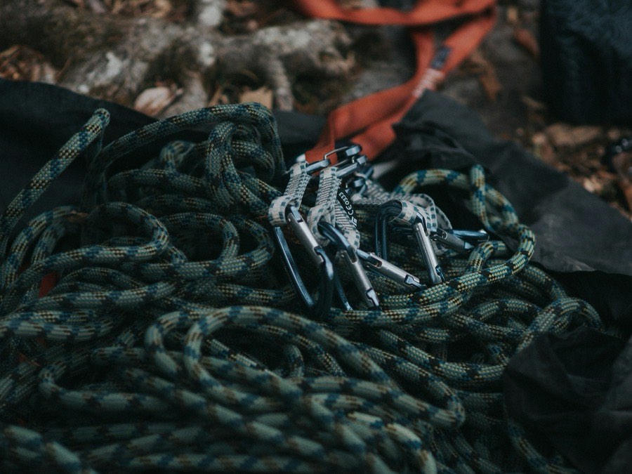 A coiled climbing rope with carabiners and a harness, ready for use